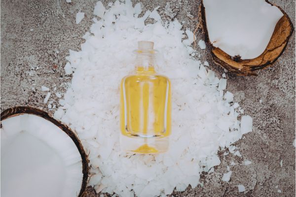 Flacon d’huile de coco entouré de noix de coco fraîche